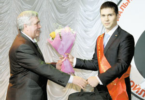 ветеран-нефтяник В. Симонов вручает подарки молодому специалисту Н. Лукманову